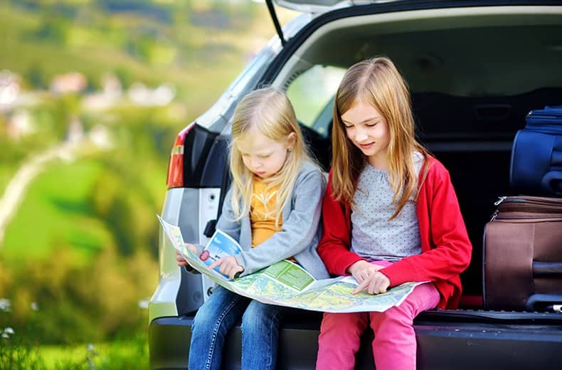 kids reading a map in a car